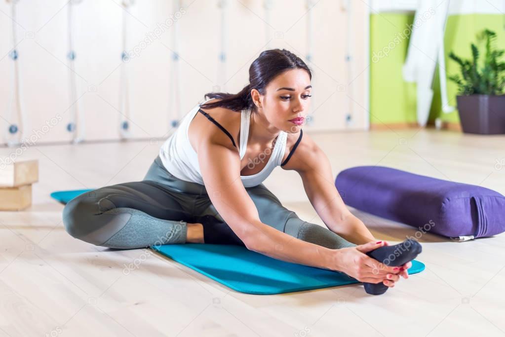 Fit woman doing stretching pilates exercises in fitness studio.