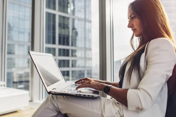 Vista lateral de la mujer emprendedora confiada usando el ordenador portátil sentado en el centro de negocios moderno —  Fotos de Stock