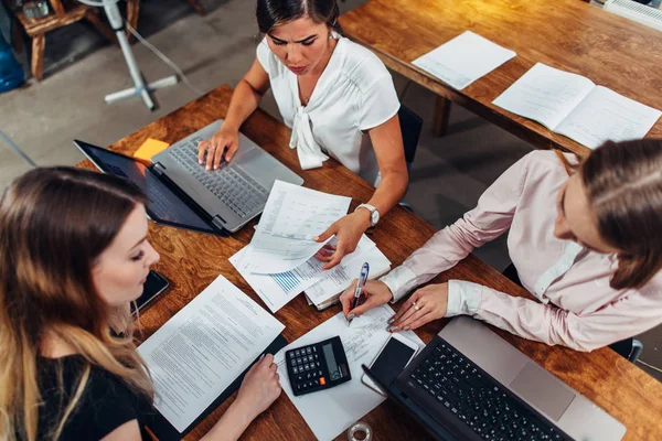 Glada kvinnliga affärspartners att ha ett möte diskuterar försäljningsstrategier i ett konferensrum — Stockfoto