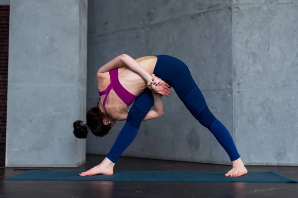 Deportiva mujer caucásica practicando de pie ángulo lateral giro posición durante la clase de yoga —  Fotos de Stock