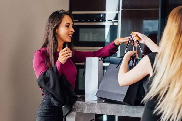 Filles élégantes gaies debout dans l'intérieur élégant avec des sacs à provisions de luxe heureux avec leurs achats — Photo