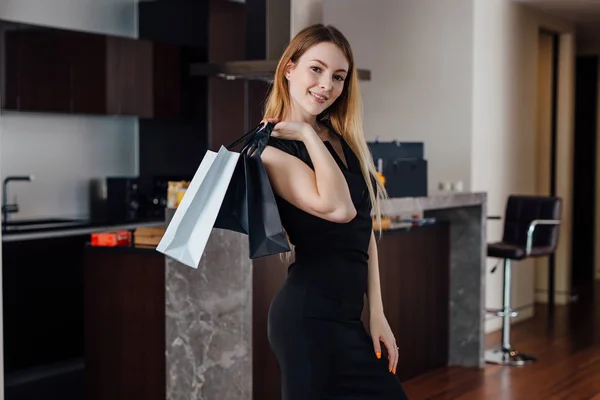 Gülümseyen genç kadın alışveriş çantası evde onun satın alma ile mutlu ile poz — Stok fotoğraf
