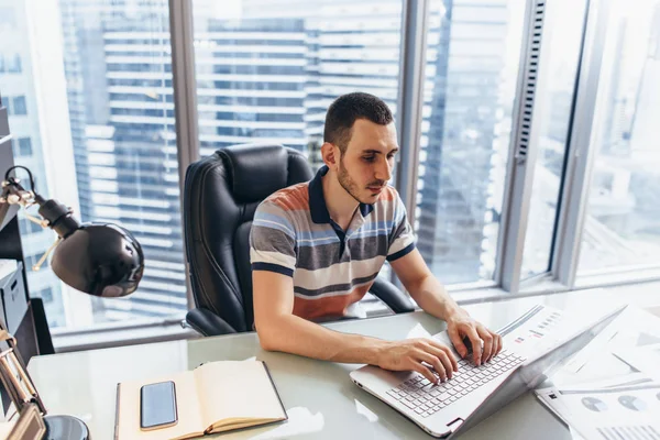 Uomo d'affari che lavora su laptop utilizzando internet alla ricerca di informazioni seduto alla scrivania in ufficio — Foto Stock