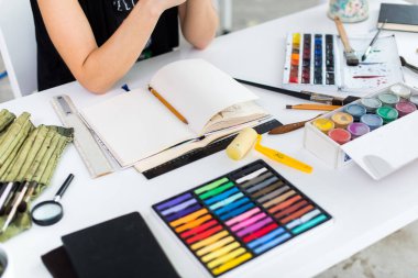 Yakın çekim Taslak çizim kalem kullanarak sketchbook bir kadın ressam görüş açısı. Sanatçı boya kalemi seti ile Sanat Atölyesi çizimi.