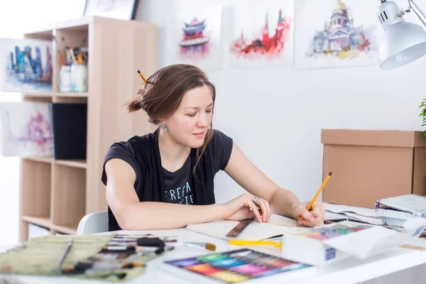 Genç kadın sanatçı ile Studio onun işyerinde kalem eskiz defteri kullanarak kroki çizim. Yan görünüm portre ilham ressam. — Stok fotoğraf