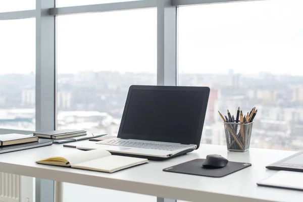 Posto di lavoro con notebook portatile Comodo tavolo da lavoro nelle finestre dell'ufficio e vista sulla città . — Foto Stock