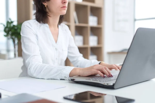 Büroangestellte tippt, arbeitet an ihrem Arbeitsplatz, benutzt Laptop. — Stockfoto