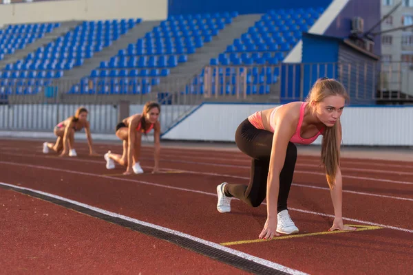 Kvinnor sprinters på startposition redo för race på travet. — Stockfoto