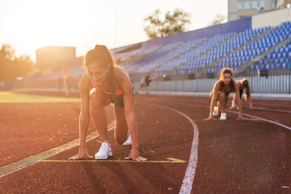 Mulheres sprinters na posição inicial pronto para a corrida em pista de corrida . — Fotografia de Stock