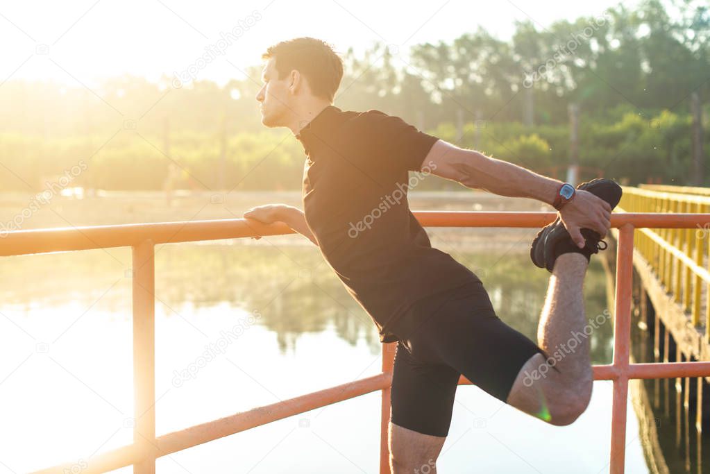 Fitness man stretching his leg before a run outdoors.