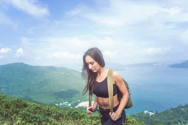 Müdes, fittes Mädchen in schwarzer Sportbekleidung auf den Hügel mit Bergen und Meer im Hintergrund — Stockfoto