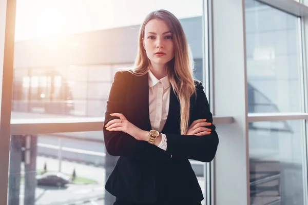 Female business traveler standing against window with airport arrival corridor view — Stock Photo, Image