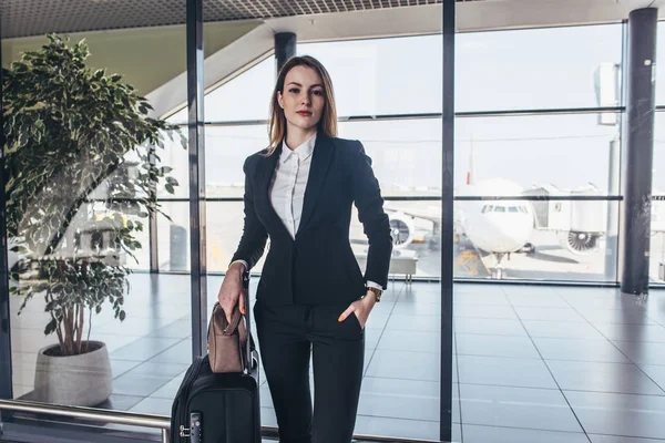 Linda aeromoça de pé em seu uniforme com suas malas prontas para um voo — Fotografia de Stock