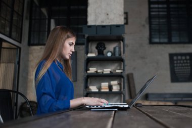 Kendine güvenen yaratıcı restoranda otururken dizüstü bilgisayarda çalışan genç kadın konsantre