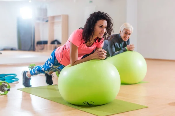 两个快乐女运动员锻炼在健身房锻炼木板瑞士球 — 图库照片