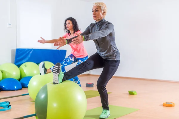 Groep van actieve vrolijke sportieve vrouwen doen één been kniebuigingen met balans bal training binnenshuis in de sportschool — Stockfoto