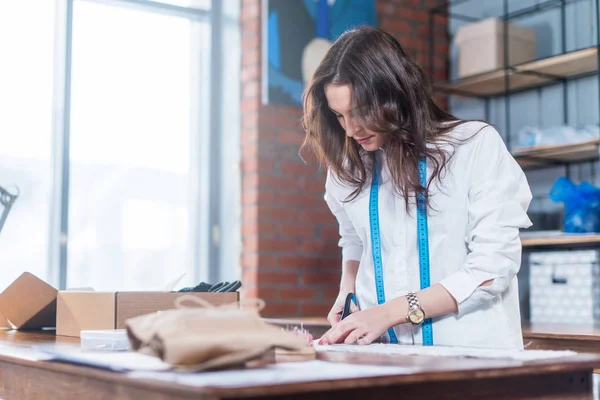 Pretty young fashion designer cutting cloth using scissors while working in studio — Stock Photo, Image