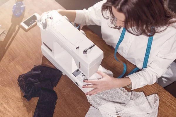 Vista superior de la tela de costura de la costurera en la máquina de coser en el lugar de trabajo en el estudio —  Fotos de Stock