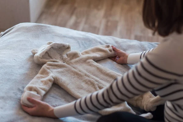 Pregnant woman dreaming and holding babys clothes — Stock Photo, Image