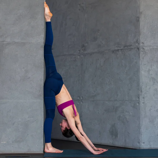 Профессиональная гимнастка, занимающаяся упражнениями на растяжку стоя, разделенная на стенки в студии — стоковое фото