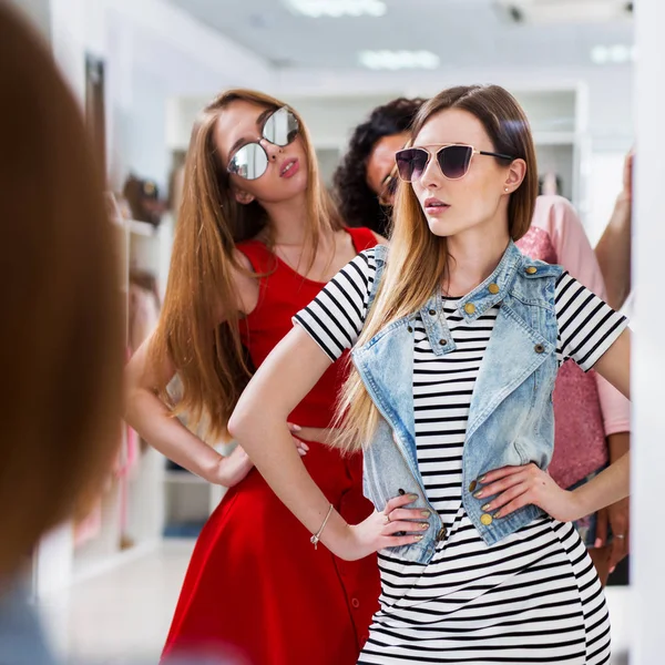 Hot jeunes femmes à la mode portant des lunettes posant dans le miroir debout dans la boutique de vêtements pour femmes — Photo