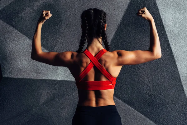 Vista posterior retrato de una mujer fitness mostrando bíceps — Foto de Stock