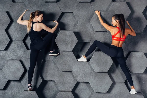 Fitte vrouwen poseren als een klimmer decoratieve muur hangen — Stockfoto