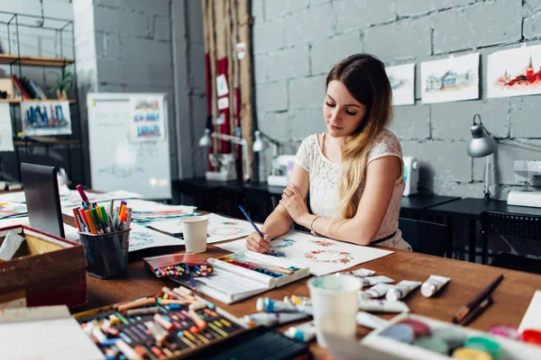 Jonge vrouwelijke artiest tekenen schetsen met kleurpotloden zittend op haar stijlvolle workshop gericht — Stockfoto