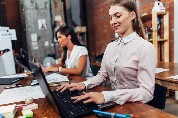 友好的女性办公室工作人员穿着正式工作服打字在笔记本电脑键盘工作在创意机构 — 图库照片