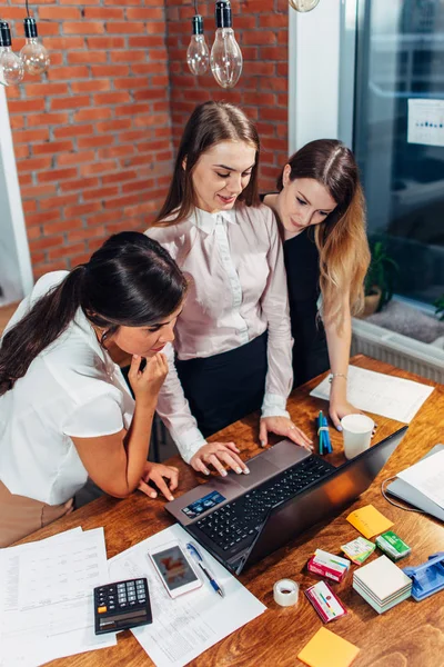 Tre kvinnliga studenter som arbetar på uppdrag tillsammans med laptop stående hemma — Stockfoto