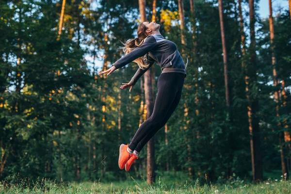 Pretty female gymnast practicing outdoors doing back bend jump — Stock Photo, Image