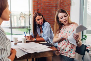 Üç kadın grup okuma ders notları bir odada masada oturan sınav hazırlama