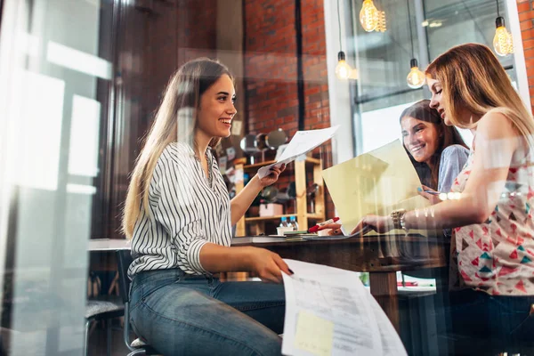 College female students sitting at table working on school assignment in a library — Stock Photo, Image