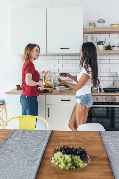 Dos mujeres en cocina cocinando hablando preparando comida . — Foto de Stock