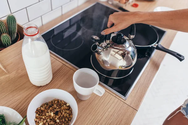 Frau erhitzt Wasser in Wasserkocher, um Kaffee zu kochen. — Stockfoto