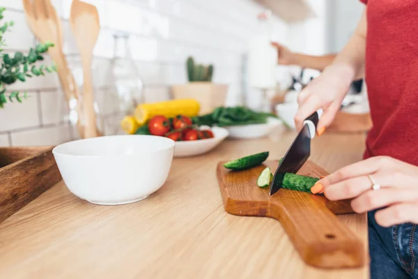 Frau schneidet Gurke auf dem Holzbrett. — Stockfoto