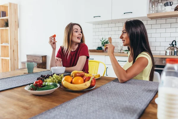Mulheres amigas tendo frutas no café da manhã na cozinha . — Fotografia de Stock
