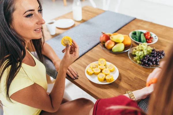 Vrouwen vrienden eten van groenten en fruit in de keuken. Gezonde voeding. Caloriearme maaltijd. — Stockfoto