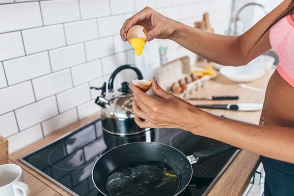 Passen van de vrouw in de keuken kraken ei in de koekenpan. — Stockfoto