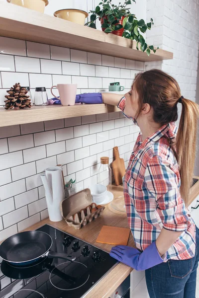 Frau in Handschuhen putzt Möbel mit Lappen in der heimischen Küche. — Stockfoto