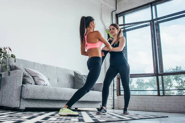 Fit meisjes benen training voorbereiden. Been uitrekkende oefening fitness vrouw doen warming-up, hamstring spieren rekken permanent thuis. — Stockfoto