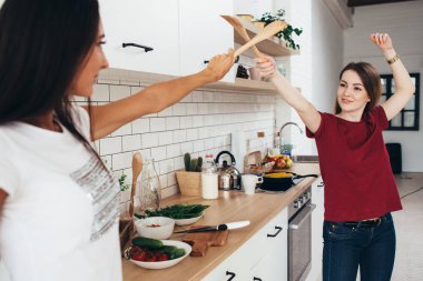 Mutfakta tahta spatula ile kılıç üzerinde savaşıyorlar iki kadın resim