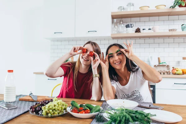 Girls fooling around in the kitchen playing with vegetables. — Stock Photo, Image
