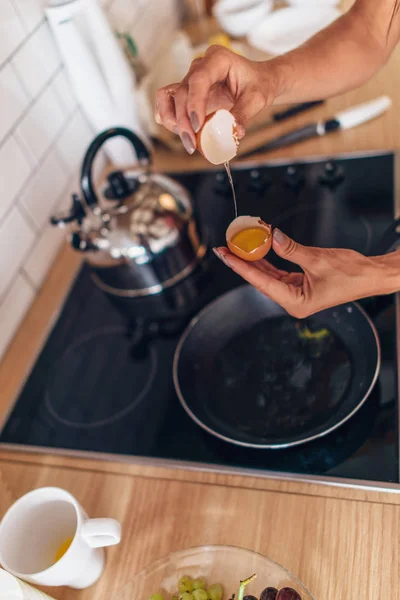 Fitte Frau in Küche knackt Ei in Pfanne — Stockfoto