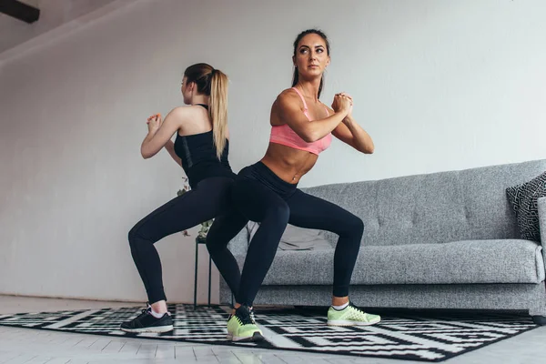 Duas mulheres aptas a fazer agachamentos em casa Feminino treino esporte e fitness — Fotografia de Stock