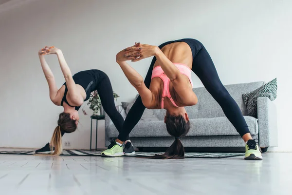 Fitness mujeres espalda estiramiento de entrenamiento en casa. Joven delgado chica hace adelante curva —  Fotos de Stock