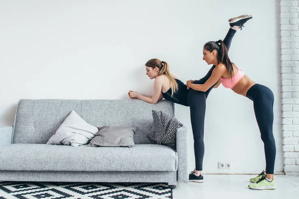 Lányok készülő lábak edzés illeszkedik. Láb nyújtó gyakorlat fitness nő ezzel a bemelegítés, a megbénít izmok nyúlik, állandó otthon. — Stock Fotó