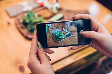 Gıda fotoğrafçılığı için sosyal ağlar. Telefon ile gıda sağlıklı yemek ekran alarak fotoğrafa tutan eller yakın çekim görüntüsü