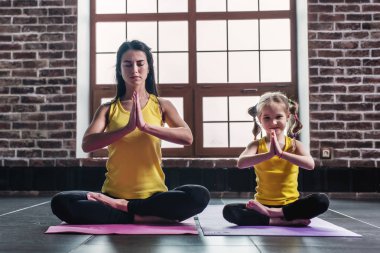 Anne ve kızı Padmasana mindere evde rahatlatıcı oturan yoga egzersizleri yaparken gülümseyen