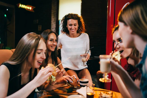 Skupina mladých kamarádek na obědě v restauraci rychlého občerstvení jíst hamburgery řemesla — Stock fotografie